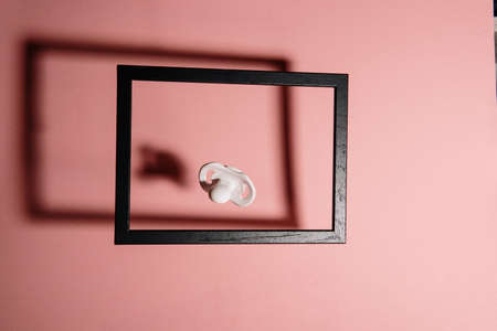 White pacifier in a picture frame on pink backgroundの写真素材