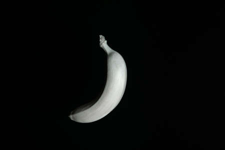 White floating banana on a black background. Left side. Creative fruit conceptの写真素材