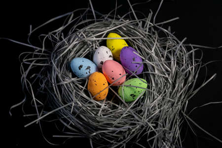 Colorful eggs in a handmade basket on black background. Creative eastern backgroundの写真素材