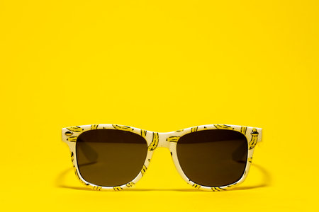 Funny banana floating sunglasses for kids on yellow backgroundの写真素材