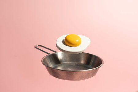 Toy egg levitate above frying pan. Creative food concept