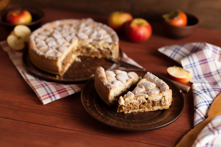 Delicious and warm homemade apple pie on a wooden table. Pie on pottery. On the photo is a pie in the cut.の写真素材