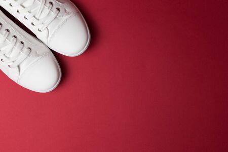 Toes of white trendy sneakers on red background. Place for text. The view from the top. Fashion blog or magazine concept.の写真素材