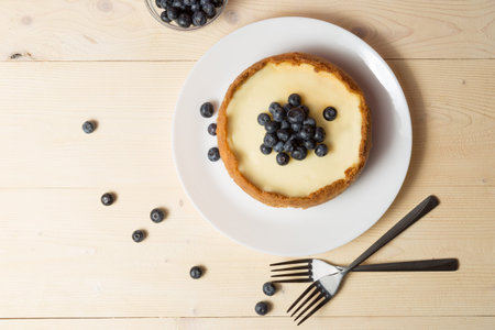 Plate with delicious cheesecake and two forks on wooden table