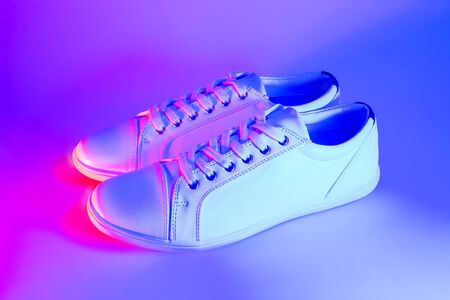 White trendy fashionable sneakers in neon light.の写真素材