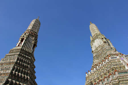 two pagodas at Wat Arun Rajwararam against blue skyの写真素材