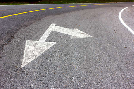 Road arrow direction sign on the asphalt road の写真素材