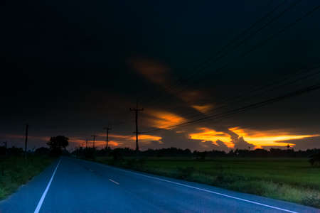 paved country road with surprisingly beautiful sky at sunset.の写真素材