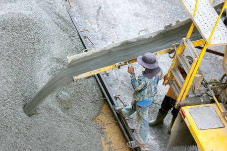 Construction worker pouring concrete from cement truckの写真素材