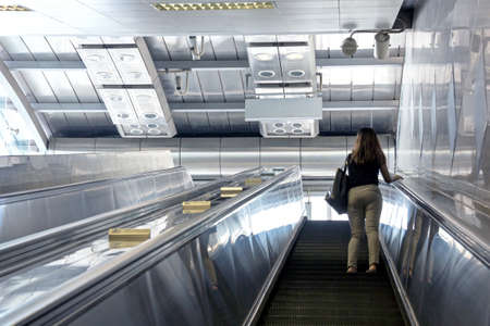 woman going up escalator at metro stationの写真素材
