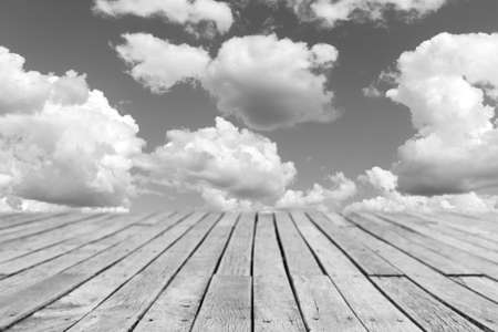 wooden planks walkway and cloudy blue sky background, black and white photoの写真素材
