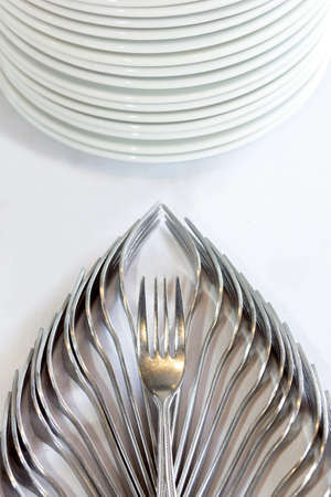 decorative fork and ceramic dish on white tablecloth, table setting for a partyの写真素材