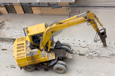 concrete crusher and hydraulic crushing hammer demolishing reinforced concrete road