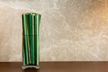green sedge leaf in jar on the wood table and marble wallの写真素材