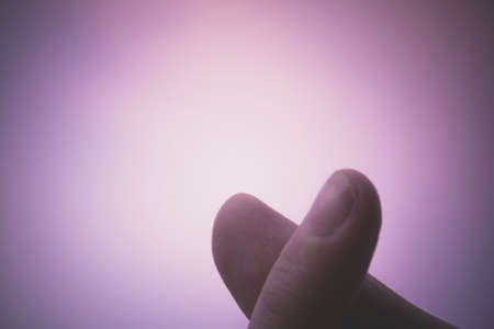 silhouette of crossed fingers in heart form as the symbol of mini heart in pink sky background with copy space. soft focus, vintage photo and film style.の写真素材