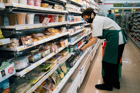 Bangkok, Thailand - August 3, 2020 : asian woman shop assistant wearing hygiene face mask are...