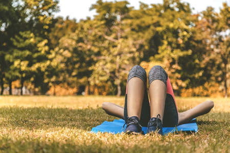 young teen women in sport suit lay down to sleep and relaxing on the green grass in the park after running exercise in summer morning with warm sunlight. people and lifestyle conceptの写真素材