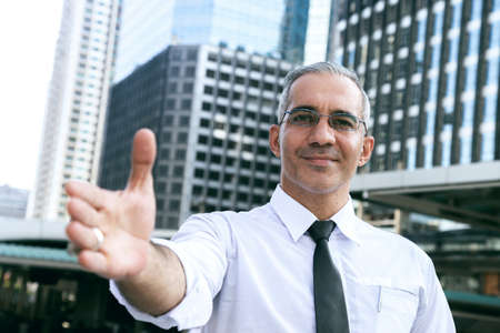 confident success businessman professional making handshake in front of office building at business center in the city after giving opportunity for new partner. business and partnership concept.の写真素材