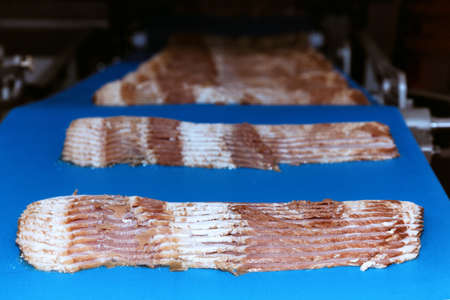 raw rasher bacon slide ready to pack in packaging on conveyor belt of automation meat slide machine in the food factory. manufacturing machinery and food  industry conceptの写真素材