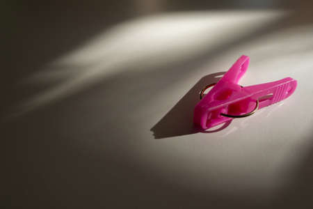pink plastic cloth clip on the floor with light, shade and shadow from the window with copy space.の写真素材