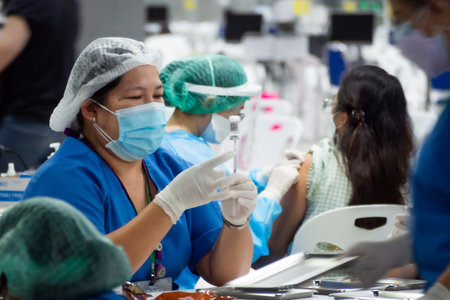 Bangkok, Thailand - November 13, 2021 : nurse or volunteer taking coronavirus vaccine into syringe for injecting covid  booster vaccination to protect people from new wave covid-19 epidemic.のeditorial素材