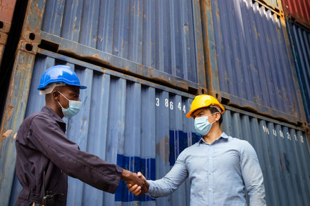 african worker and caucasian businessman wearing face mask to protect from covid or coronavirus are...