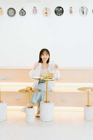 A girl eating happily in a cafの写真素材