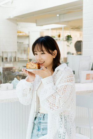 Asian young girl enjoying her cake in a cafe.の写真素材