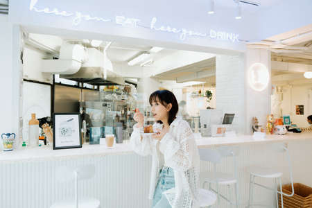 Asian young girl enjoying her cake in a cafe.の写真素材