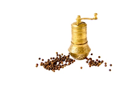 Oriental brass pepper mill and black peppers isolated on white backgroundの写真素材