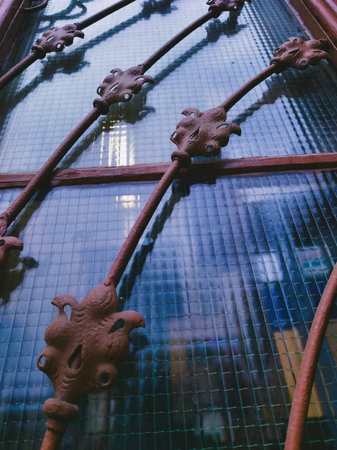 Close-up of a historic window featuring decorative wrought iron and aged textures. Capturing the...