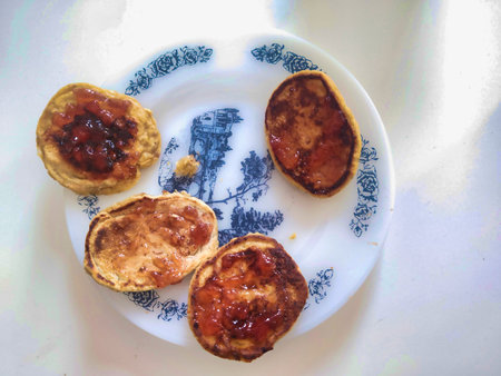 A top-down shot of four golden pancakes topped with fruit jam. Captured in a sunlit Budapest home,...