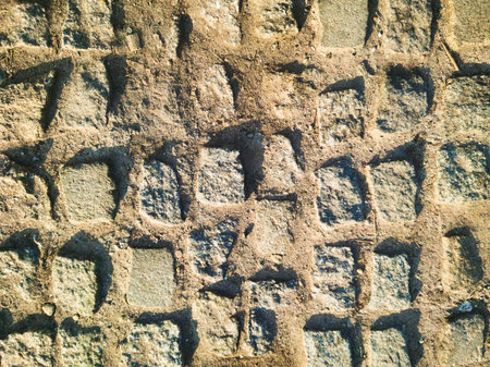 Rhythmic shadows fall across a historic cobblestone street in Budapest. This high-quality urban...