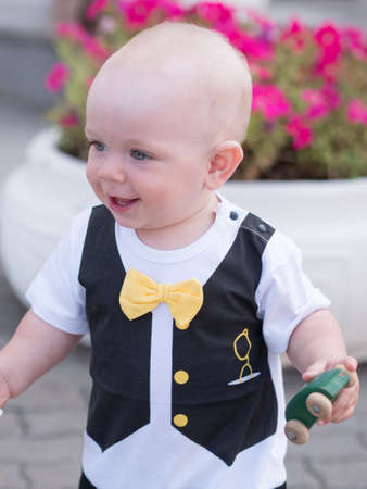 Beautiful toddler walking with his mother on a city holiday. Kid stylishly dressed with a butterfly and a cap.の写真素材