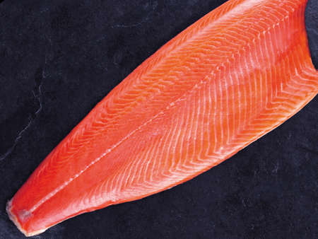 Fresh raw salmon background. Salmon steak with fresh herbs on black background, flat lay.の写真素材