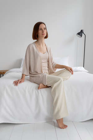A young girl in beige clothes sits in a white cosmetology roomの写真素材
