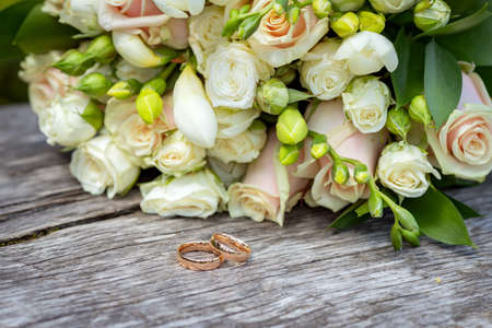 Beautiful wedding bouquet with wedding rings on a wooden tableの写真素材