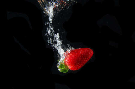 strawberry splashing in water in white backgroundの写真素材