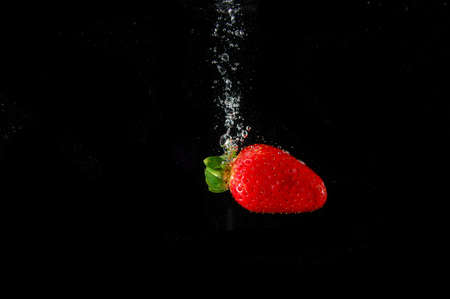 strawberry splashing in water in white backgroundの写真素材