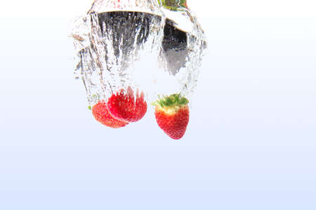 healthy strawberry fruits splashing in cool waterの写真素材