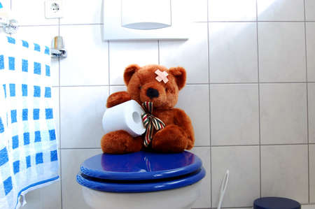 toy teddy bear with paper in the bathroom on toiletの写真素材