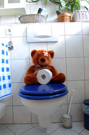 toy teddy bear with paper in the bathroom on toiletの写真素材