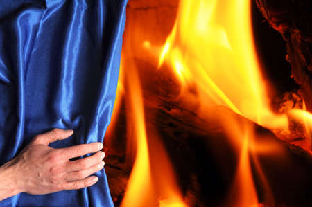 fire or flame hand and blue curtain with hand showing heatの写真素材