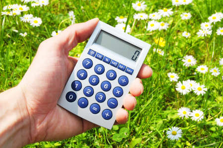ecological accounting concept with calculator in green grassの写真素材