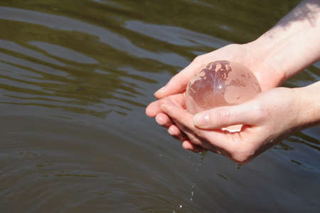 hand water and glass globe showing eco ecology or nature conceptの写真素材