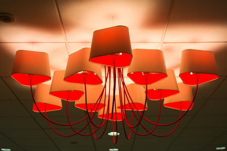 Modern industrial vintage loft style bowl lamps hanged by wire to a ceiling in a dark area of cafe or restaurant, Design or Creative red lampの写真素材