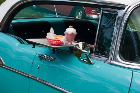 tray with burger and milk shake on classic car at drive inの写真素材