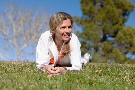 mature woman laying in grass in a park smilingの写真素材