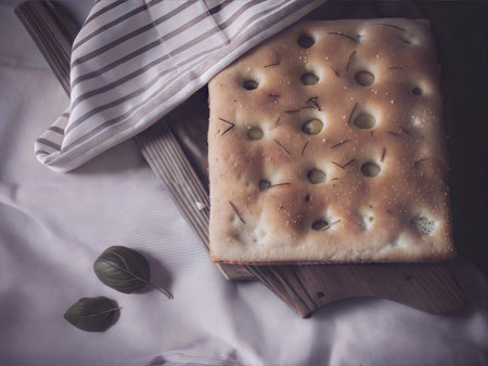 Golden-brown focaccia bread with visible air pockets and a slightly crispy crust.の写真素材