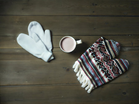 A warm and inviting flat lay featuring knitted mittens, scarves, and a mug of hot chocolate. Perfect for winter or holiday themes.の写真素材